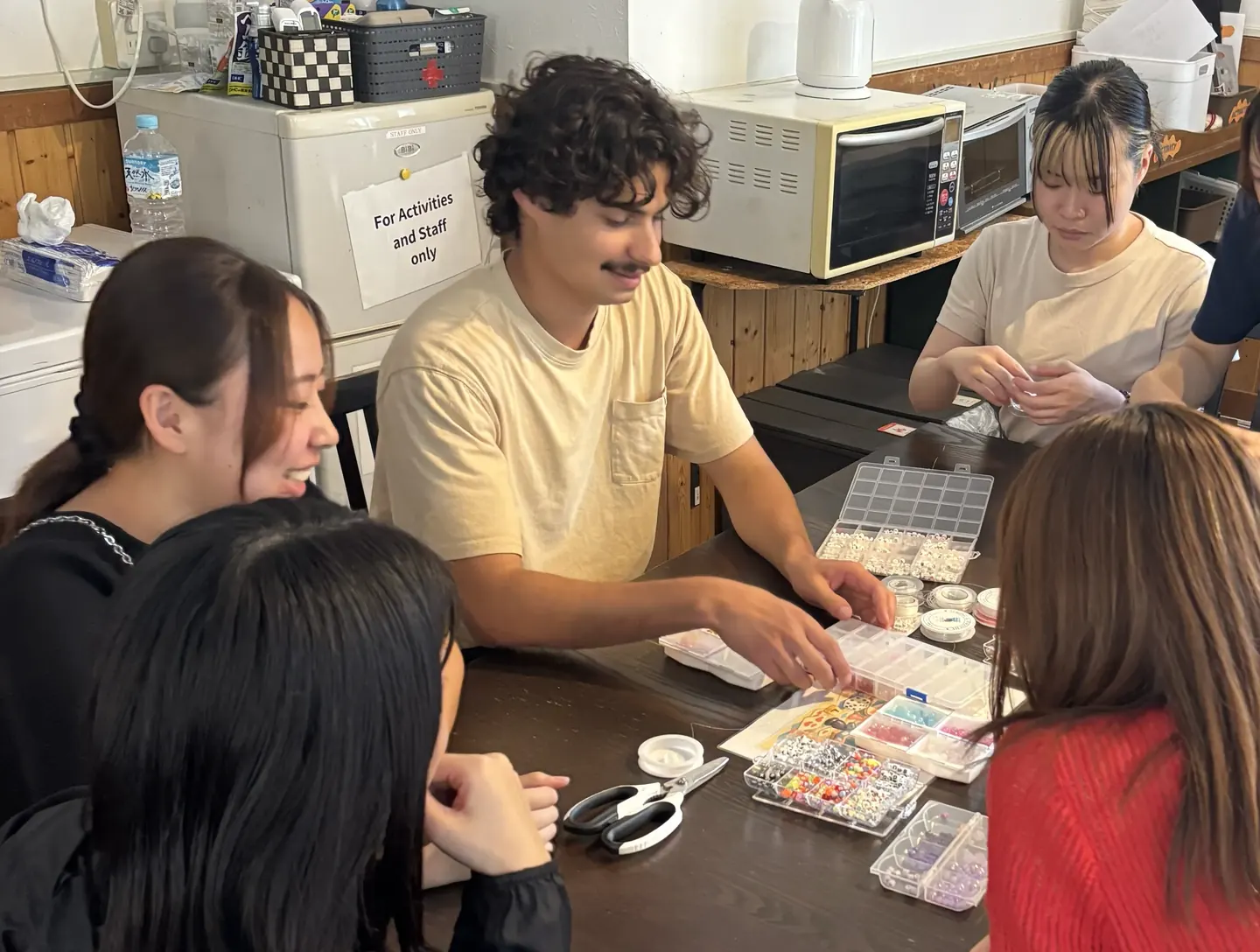 ニセコ留学のArt & Craftアクティビティで、先生と生徒がビーズを選びながらブレスレットを作っている様子